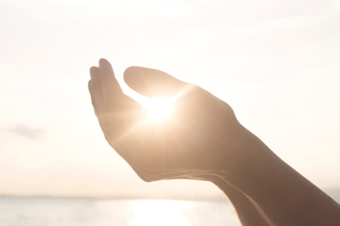 woman's hands hold the sun and its energy